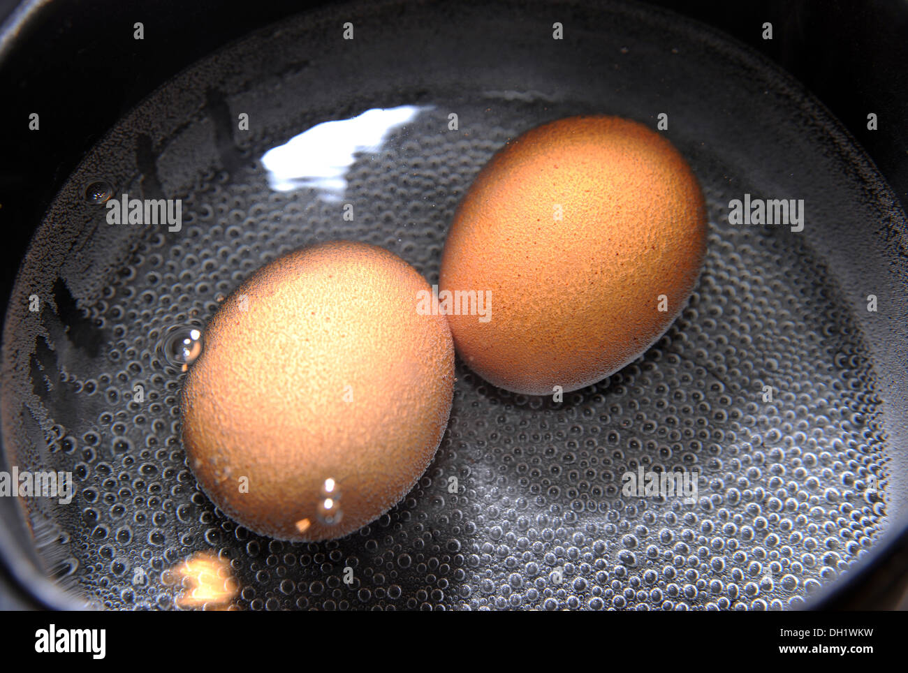 Two free range eggs boiling in a saucepan Stock Photo