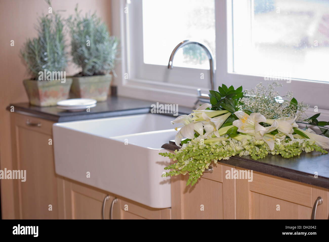 White lilies flowers on kitchen unit with slate worktop beside double