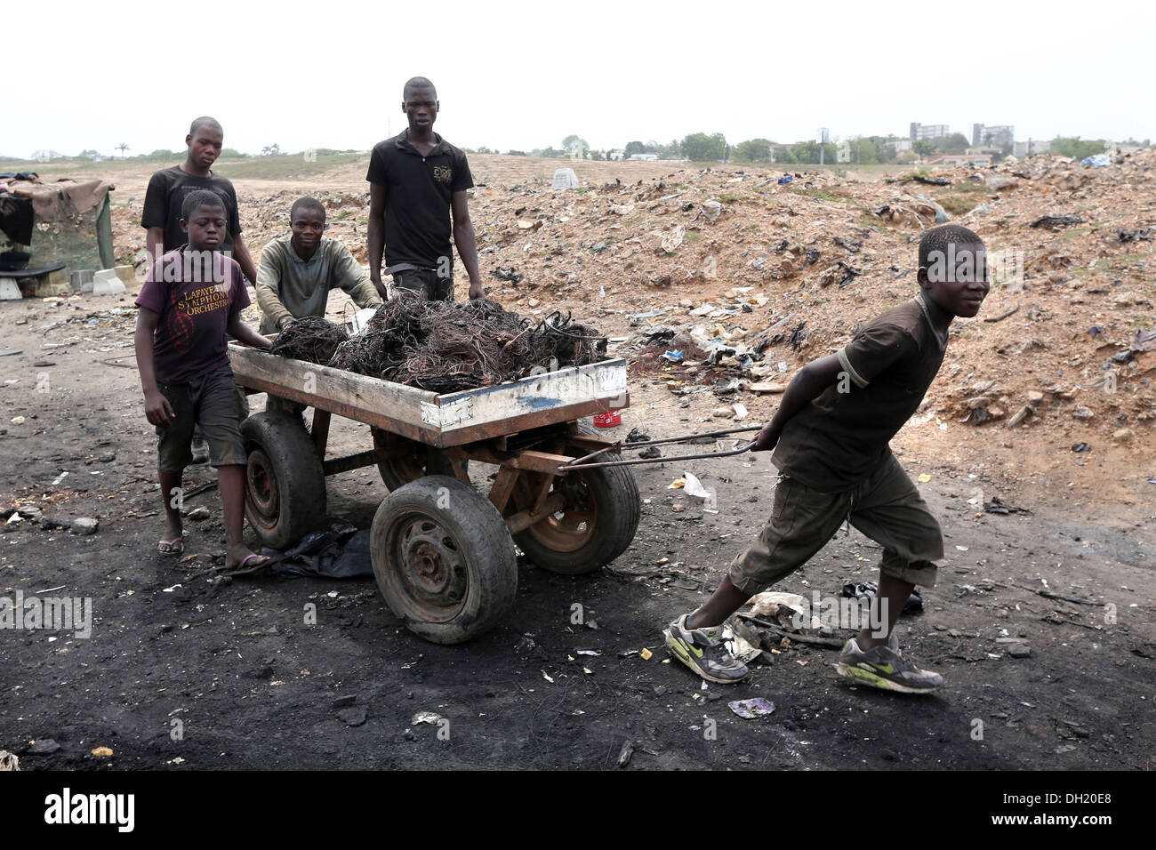 Boys pull a cart with raw copper cables from burned computers, Agbogbloshie dump site in Accra, Ghana Stock Photo
