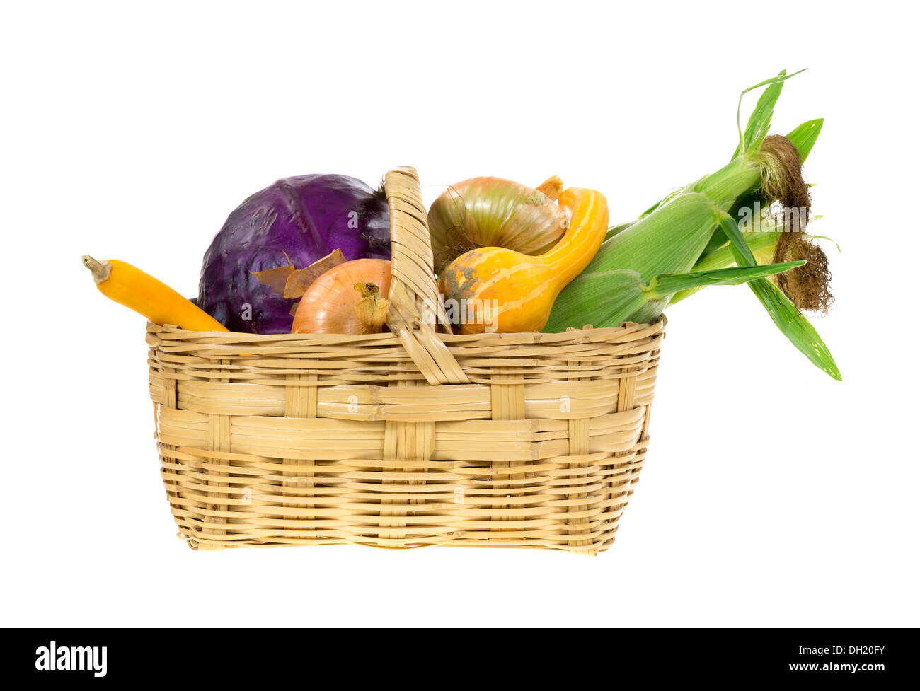 Corn, gourds, onions and red cabbage in an old wicker basket on a white background. Stock Photo