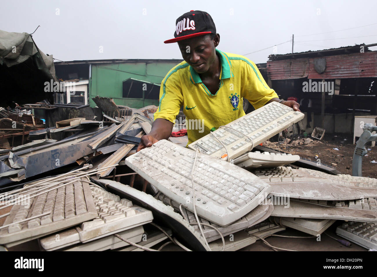 Man dismantles computer keyboards and other electronics to recover metal near the Agbogbloshie slum in Accra, Ghana Stock Photo