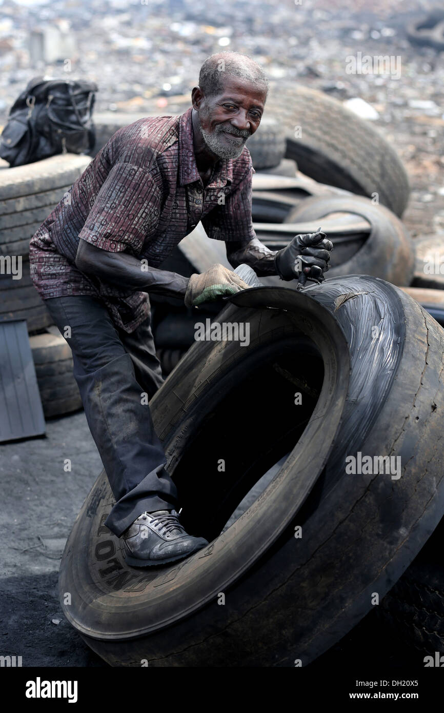 Old man makes rubber shoes from tires, Agbogbloshie dump site, Accra, Ghana Stock Photo