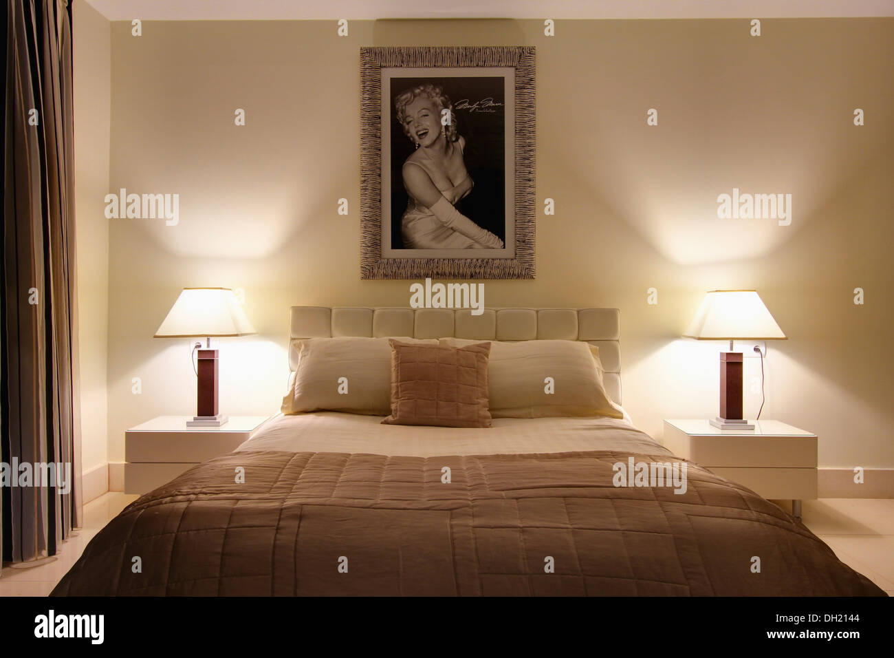 Framed Picture Of Marilyn Monroe Above Bed With Beige Quilt In