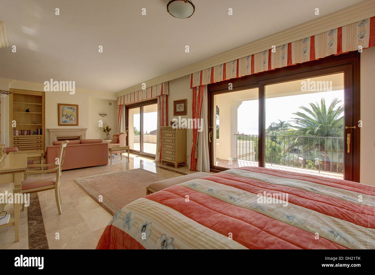 Pink striped quilt on bed in Spanish studio apartment bedroom with pink
