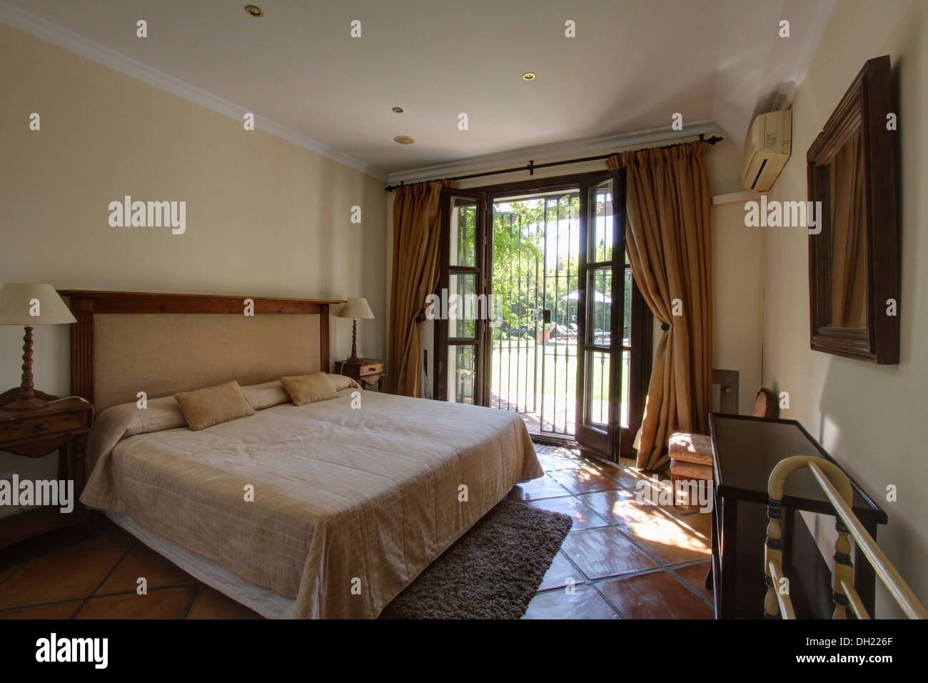 Cream bed cover on bed in Spanish bedroom with terracotta tiled floor