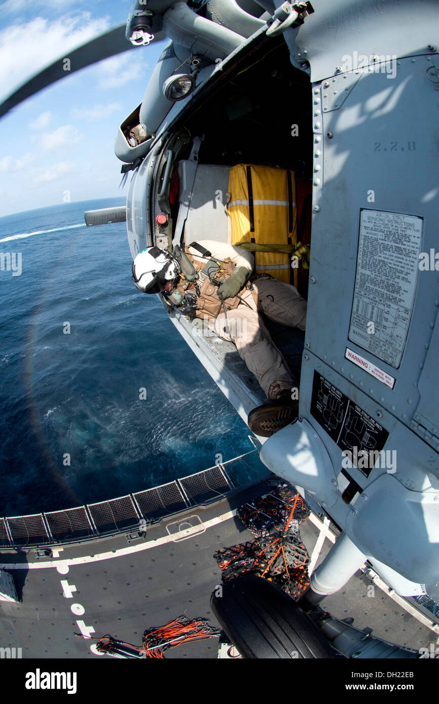 Naval Aircrewman (Helicopter) 2nd Class Aaron Stagg, assigned to the Dusty Dogs of Helicopter Sea Combat Squadron (HSC) 7, assists the pilot of an MH-60S Seahawk helicopter while conducting a vertical replenishment with the aircraft carrier USS Harry S. T Stock Photo