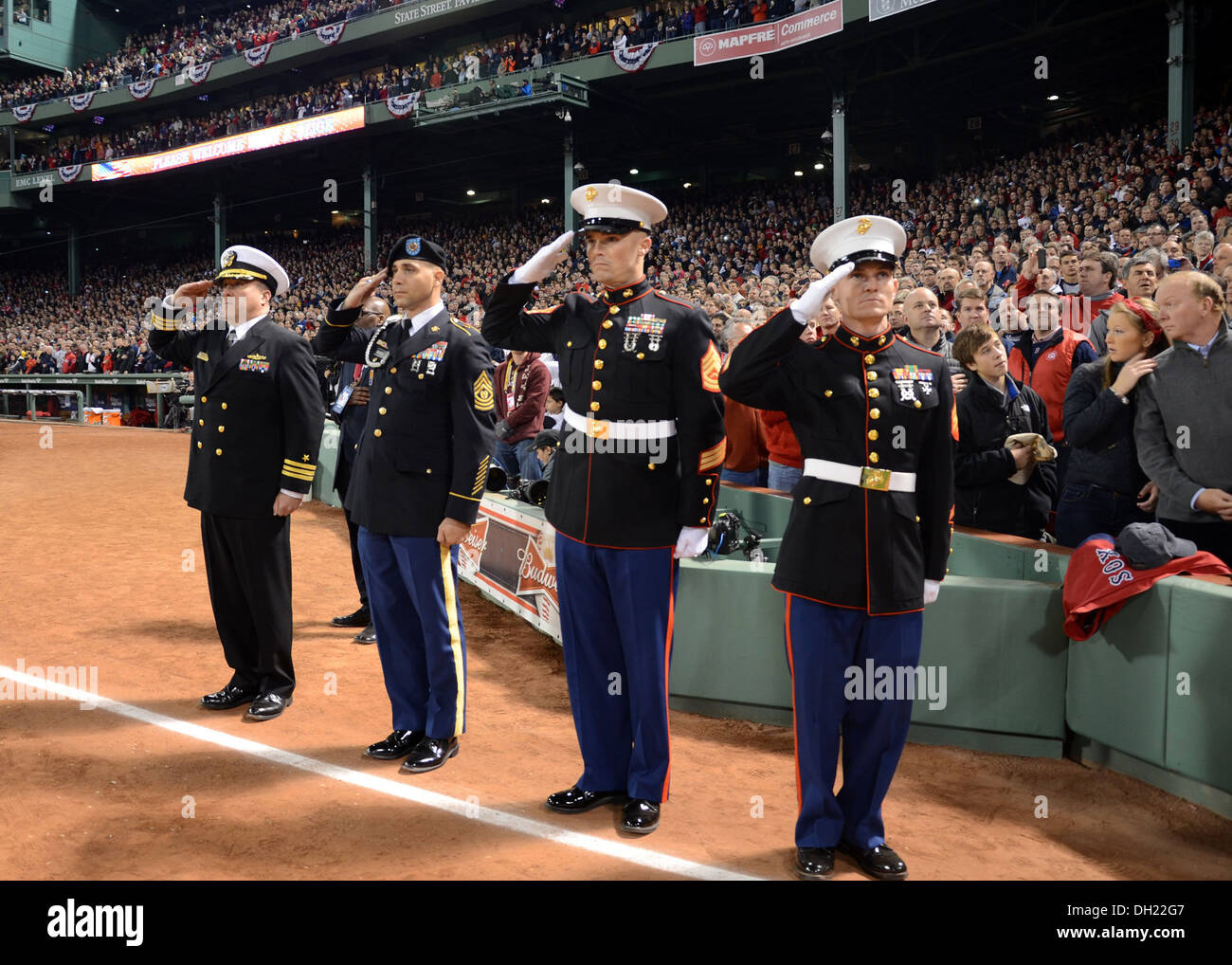 Cmdr. Sean Kearns, 73rd commanding officer of USS Constitution, far left, salutes the national ensign along with service members from the U.S. Army and Marine Corps during the singing of the national anthem at Game 1 of the World Series at Fenway Park. Sa Stock Photo
