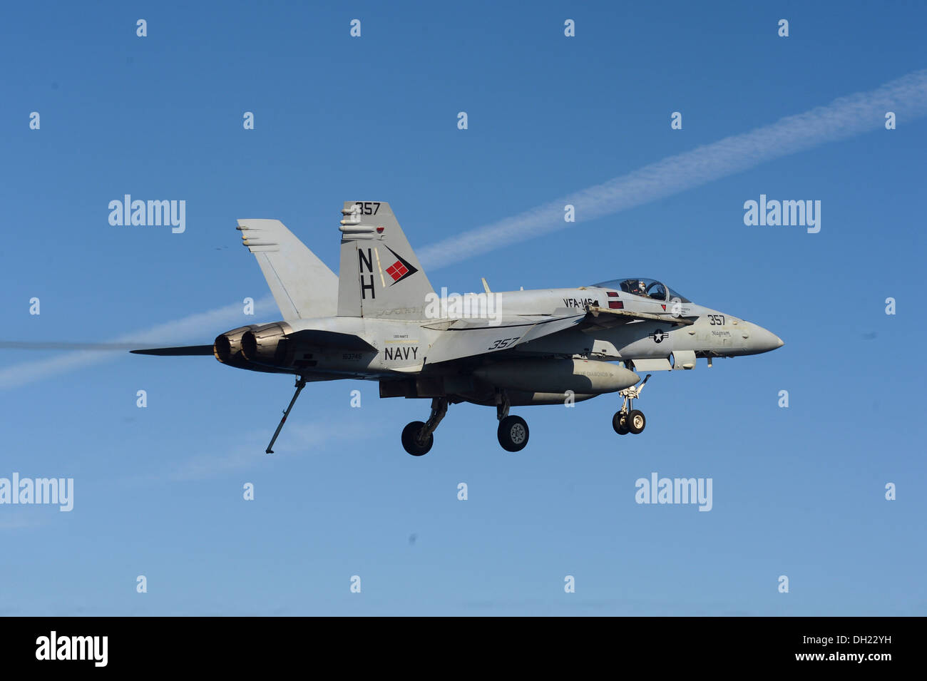 An F/A-18C Hornet assigned to the Blue Diamonds of Strike Fighter Squadron (VFA) 146 flies over the aircraft carrier USS Nimitz Stock Photo