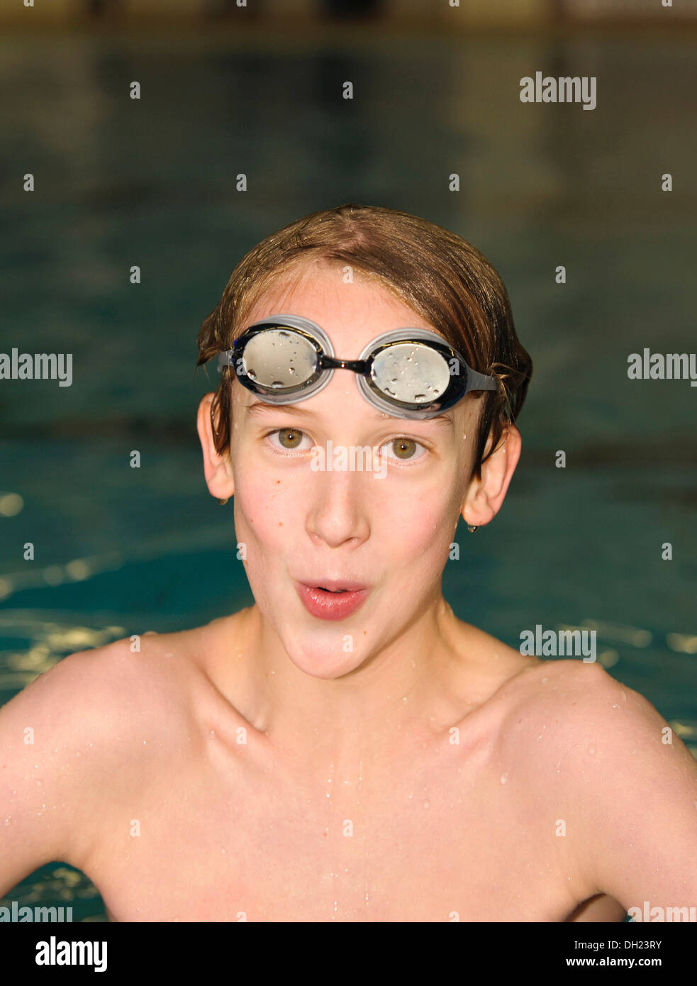 Boy, swimmer, 12 or 13 years, with swimming goggles in a swimming pool Stock Photo