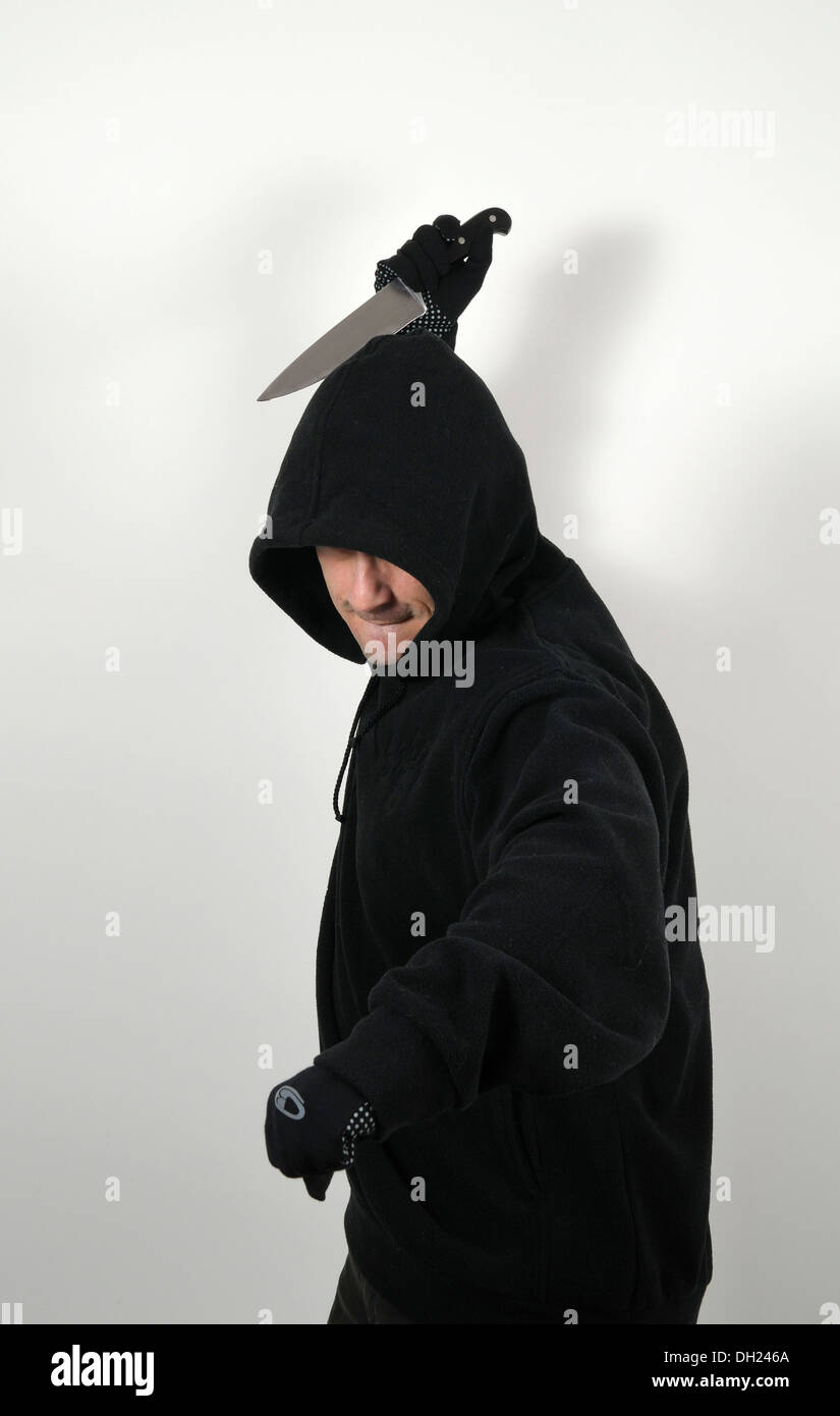 Young man with a black hooded shirt and a raised knife Stock Photo