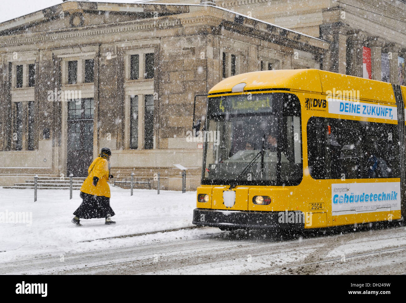 Woman rushing towards a tram in the snow in front Schinkelwache, Dresden, Saxony, PublicGround Stock Photo