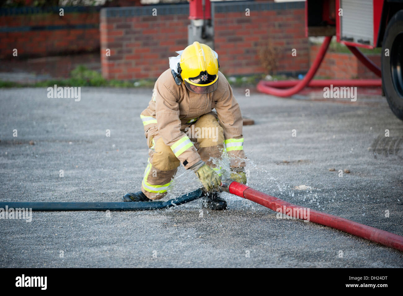 Firefighter un-coupling fire hose Stock Photo