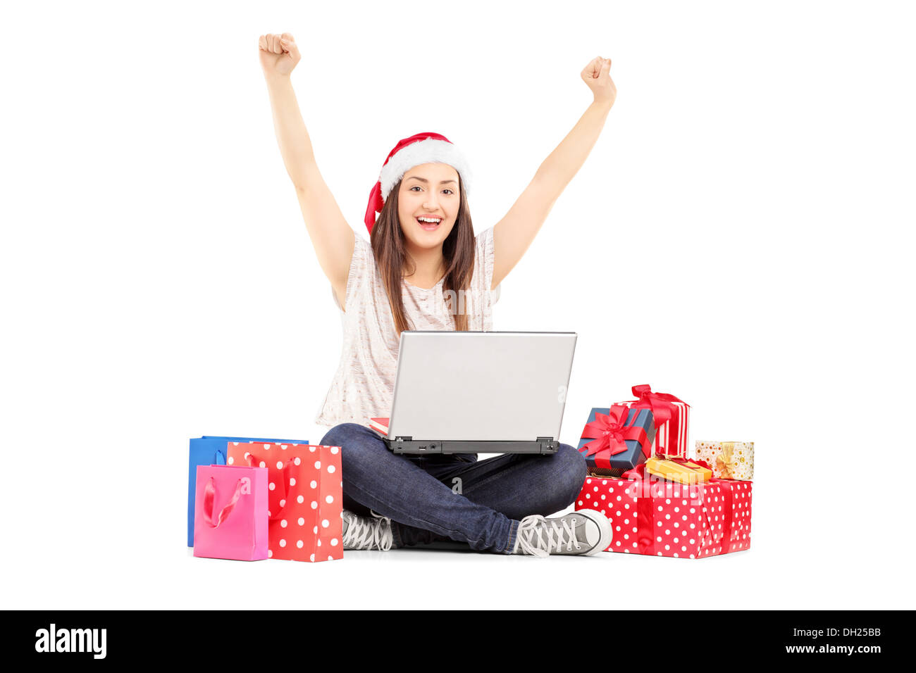 Excited young female with santa hat working on a laptop and gifts around her Stock Photo
