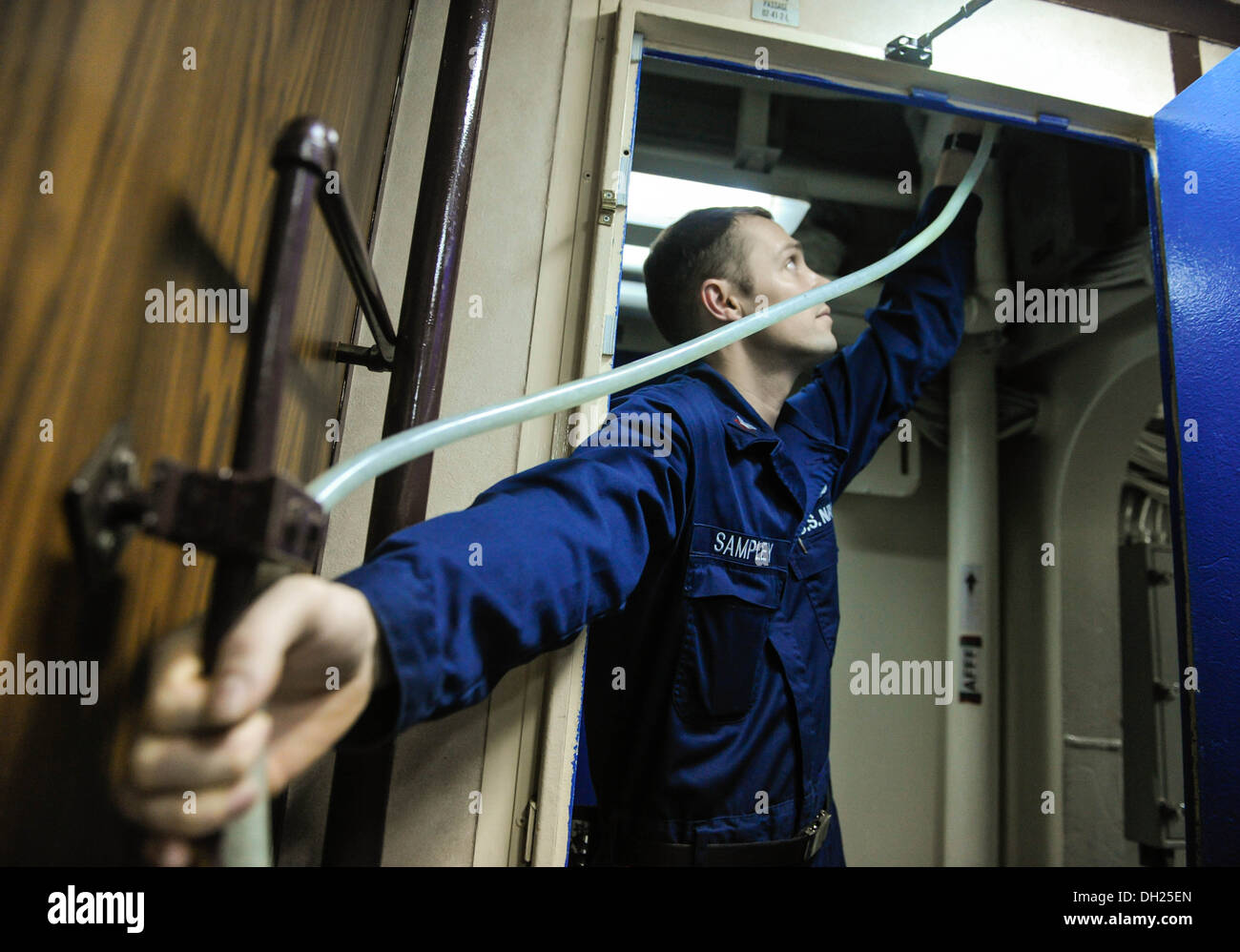 ARABIAN SEA (Oct. 22, 2013) Machinist’s Mate 3rd Class Justin Sampley bleeds air out from a pipe in the wardroom aboard the amphibious assault ship USS Boxer (LHD 4). Boxer is the flagship for the Boxer Amphibious Ready Group and, with the embarked 13th M Stock Photo