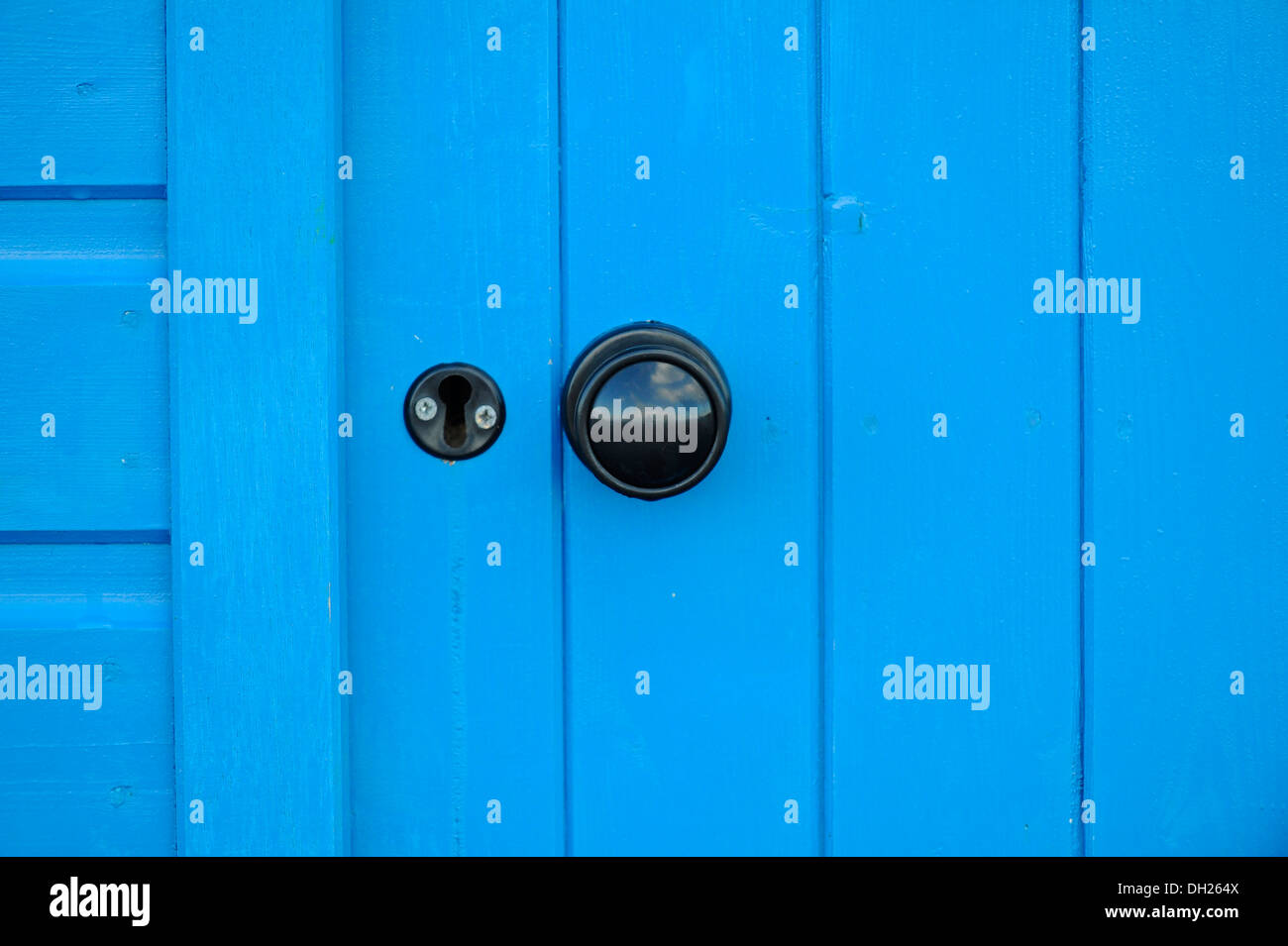 Brightly coloured wooden shed door with black round door handle and lock. Stock Photo