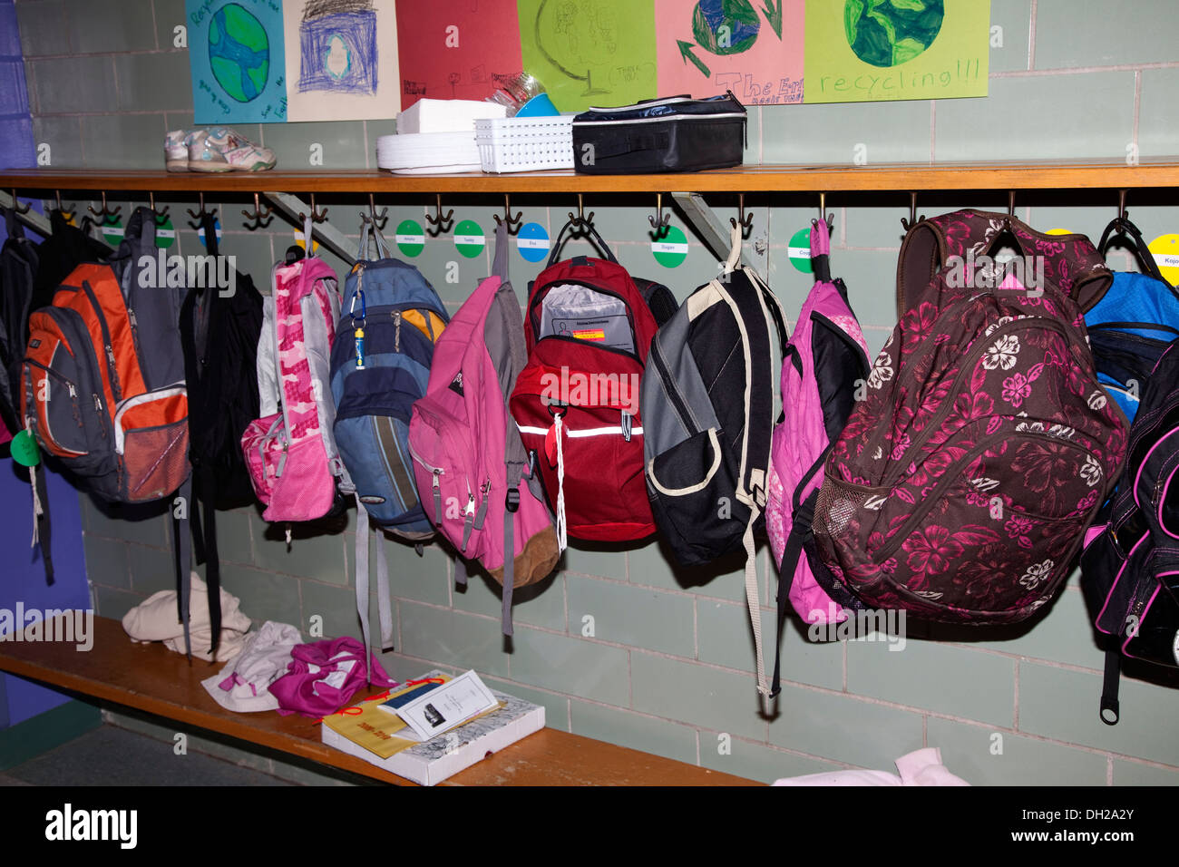Children's colorful backpacks hanging in a row on hooks. Horace Mann Elementary School St Paul Minnesota MN USA Stock Photo