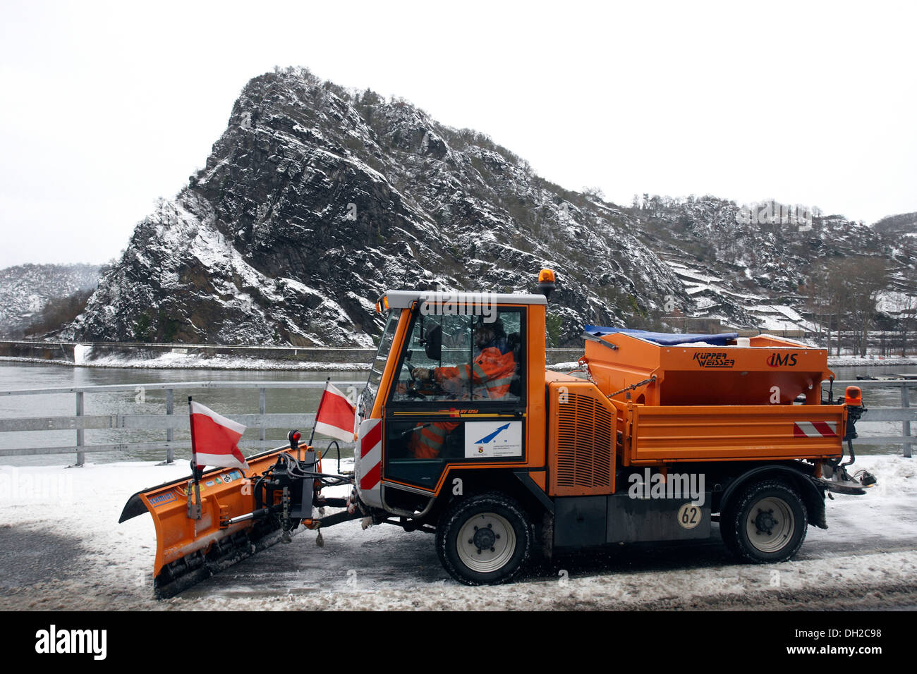 A snow plow driving past the snowy Lorelei rock in the Rheintal valley, St. Goar, Rhineland-Palatinate Stock Photo