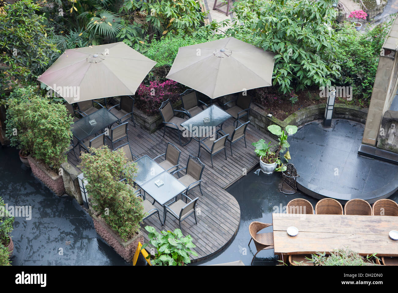 house patio with table and chairs under umbrella, there are a lot of vegetation around. Stock Photo