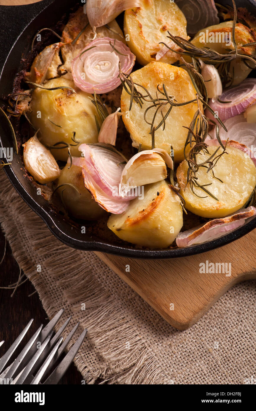 Oven-baked potatoes in skillet on wooden table Stock Photo