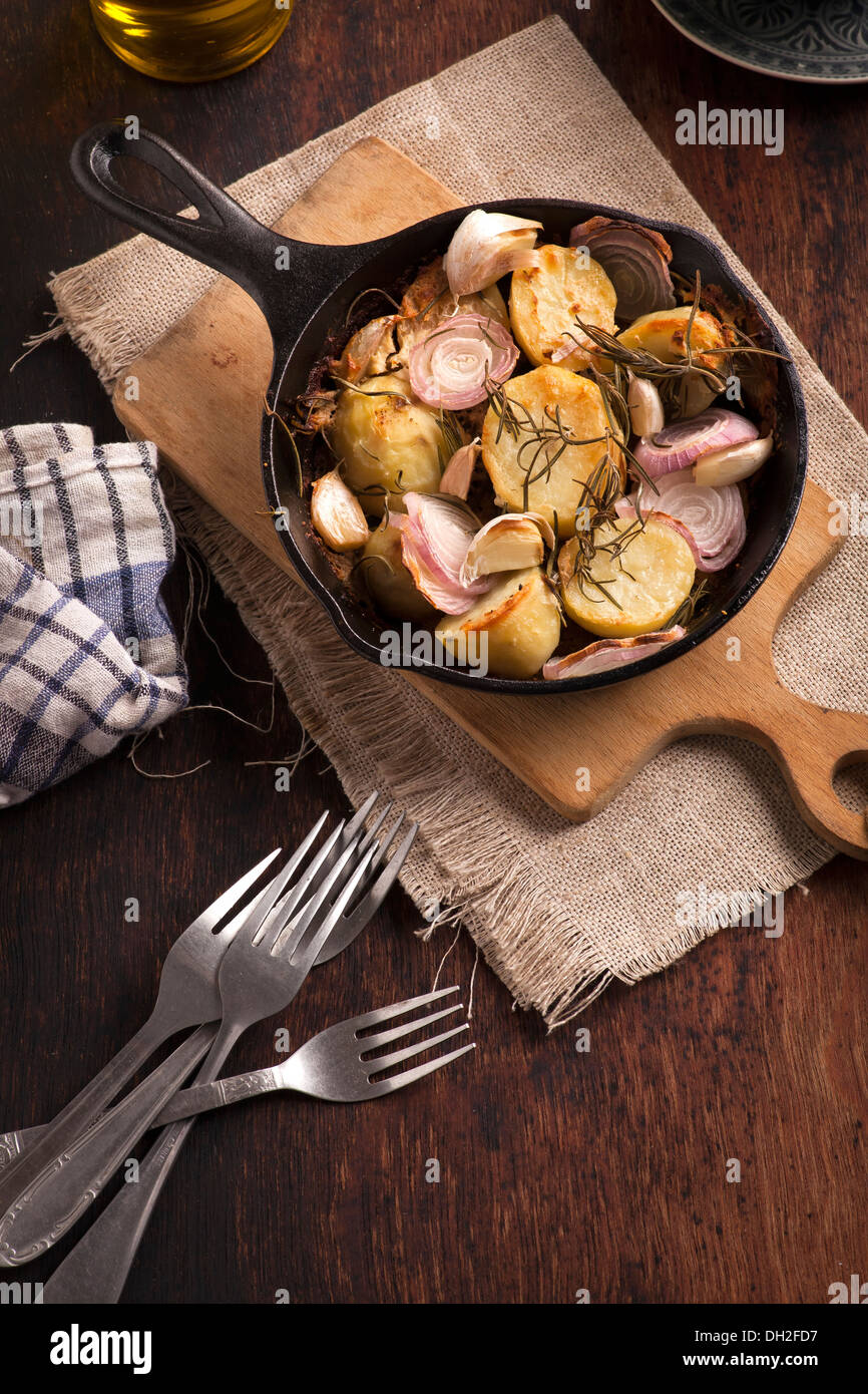Oven-baked potatoes in skillet on wooden table Stock Photo