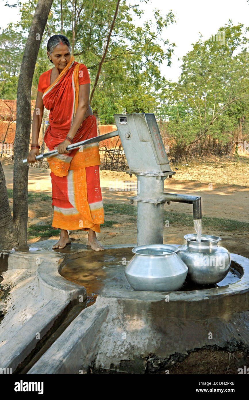 Indian woman using hand pump for drinking water from village borehole well, Jharkhand, India, Asia Stock Photo