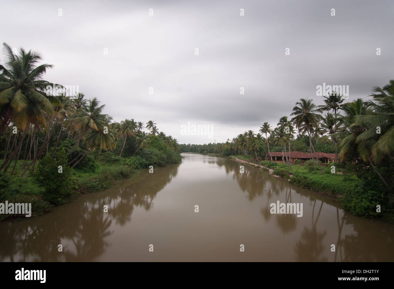 river stream with coconut trees on either sides with moving clouds on a monsoon tourist season period in kerala Stock Photo