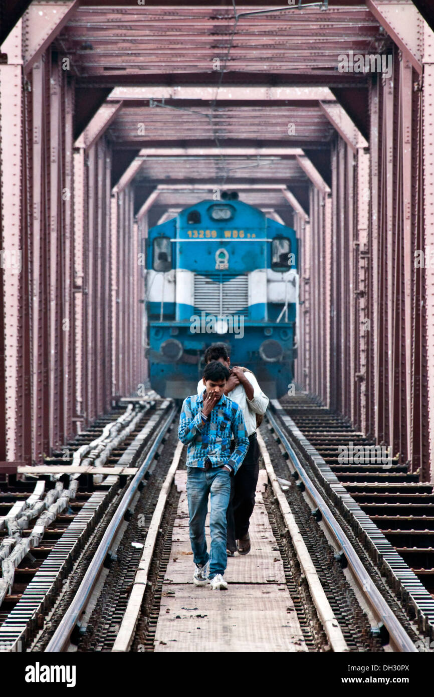 Two men walking on the railway track, oblivious of approaching train Stock Photo