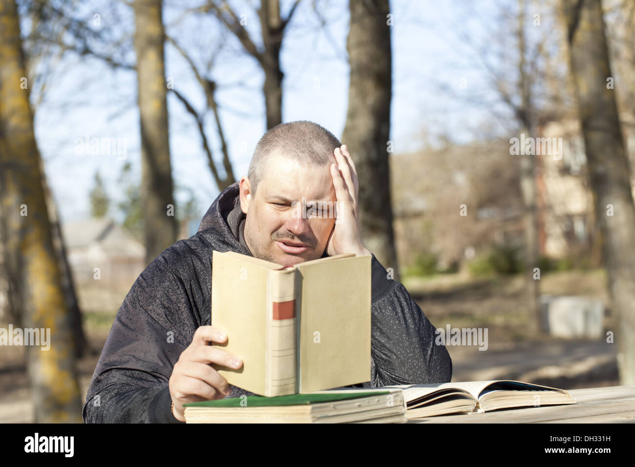 Man reading a book outdoors on a bench Stock Photo