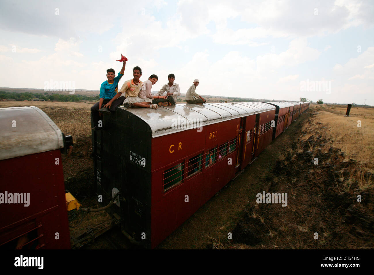 people sitting on top of railway train compartment at Miraj Maharashtra India Asia Stock Photo
