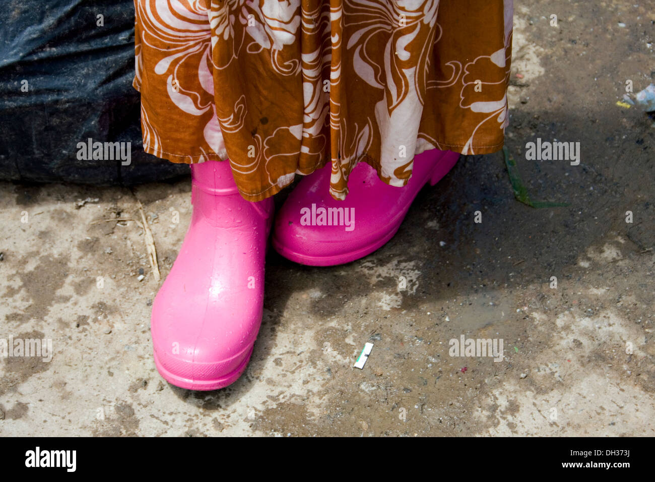 A young child laborer girl is wearing a colorful pair of waterproof galoshes near a large garbage dump in Phnom Penh, Cambodia. Stock Photo