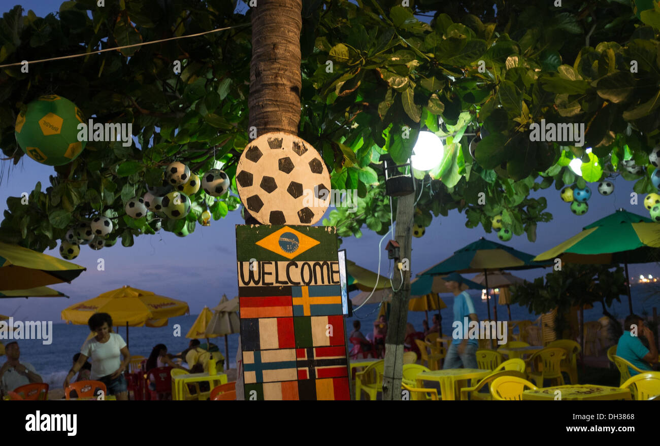 Beach restaurant/bar with football and Brazilian flag sign on tree. Fortaleza, Brazil which will wecome fans to the World Cup. Stock Photo