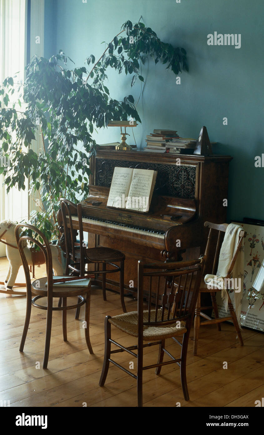 Bentwood chairs and antique piano in pale blue dining room with tall