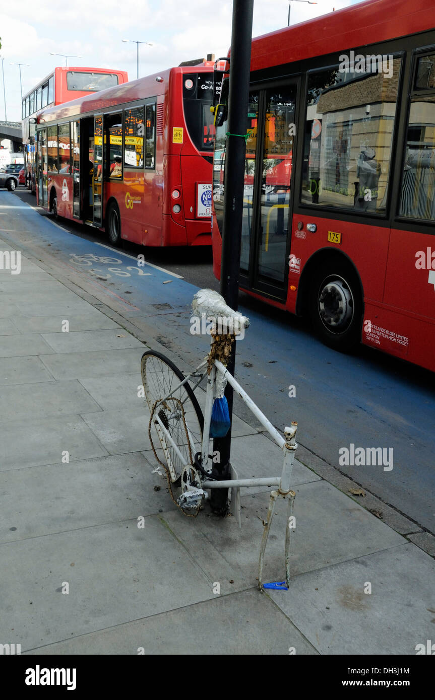 Remains of vandalised ghost bike on CS2, Barclays Superhighway Route 2 with buses close alongside Stock Photo
