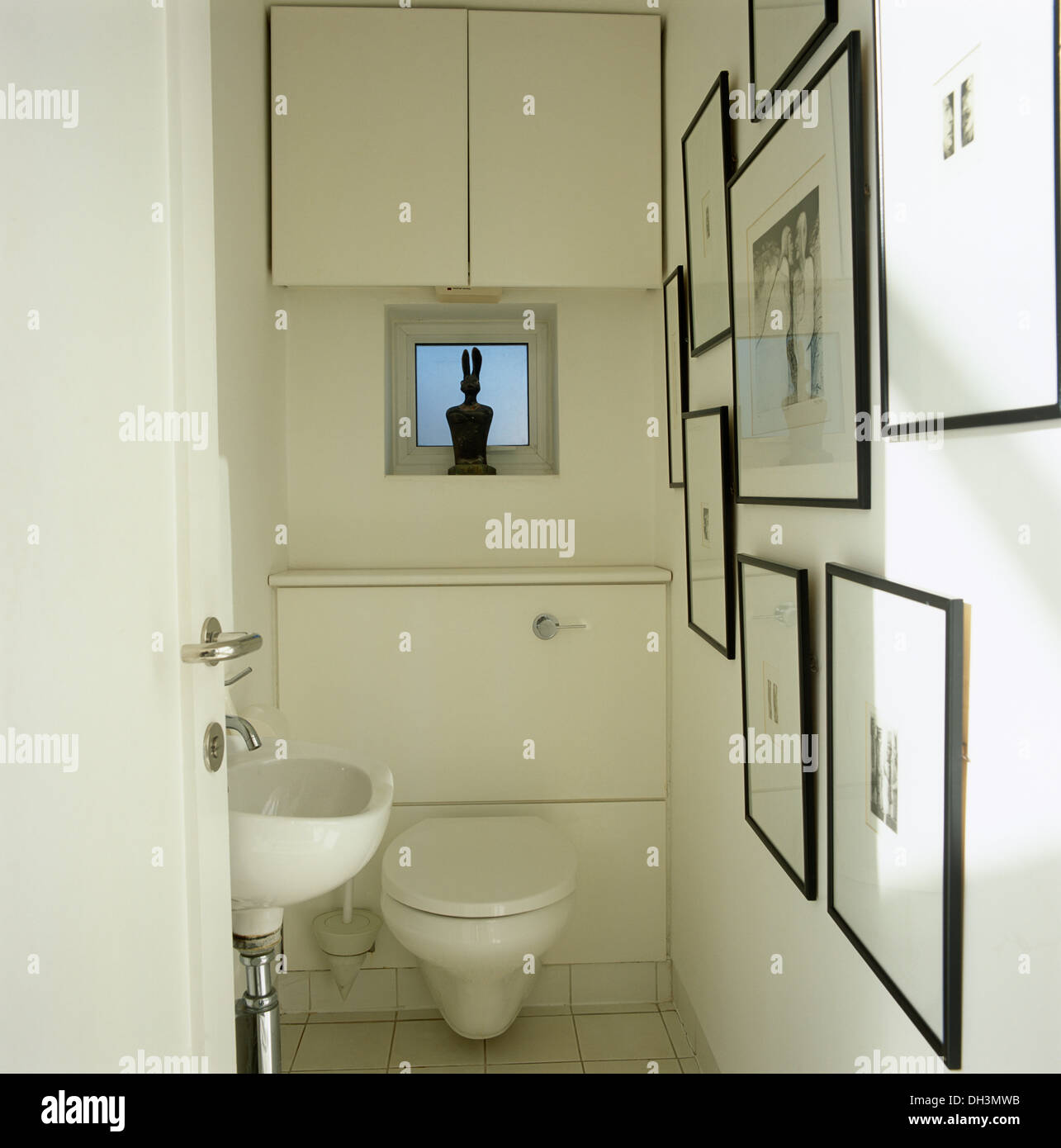 Wall cupboard and small window above toilet in cloakroom with wall