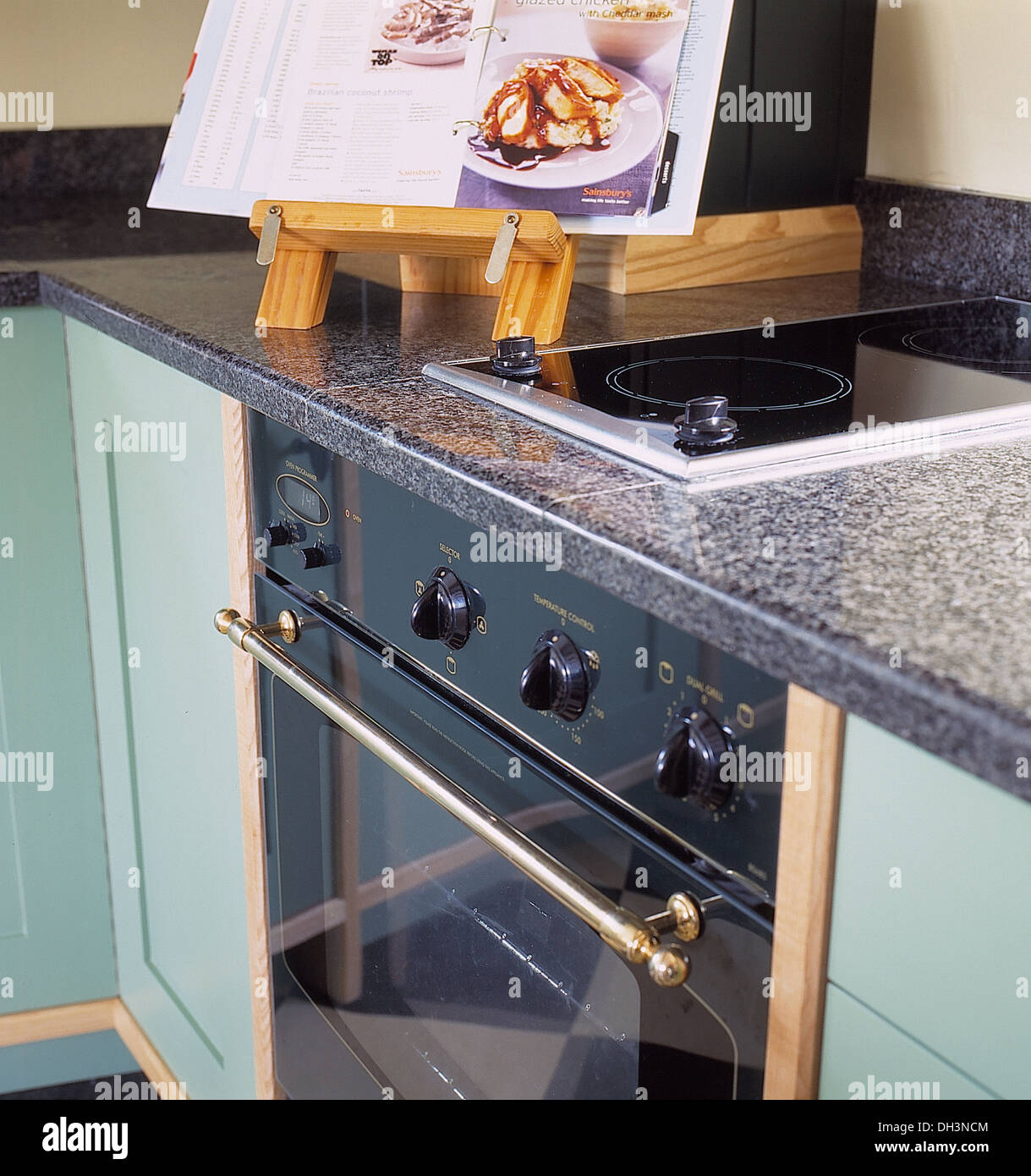 Cookery book on stand beside hob set into granite worktop in aqua blue