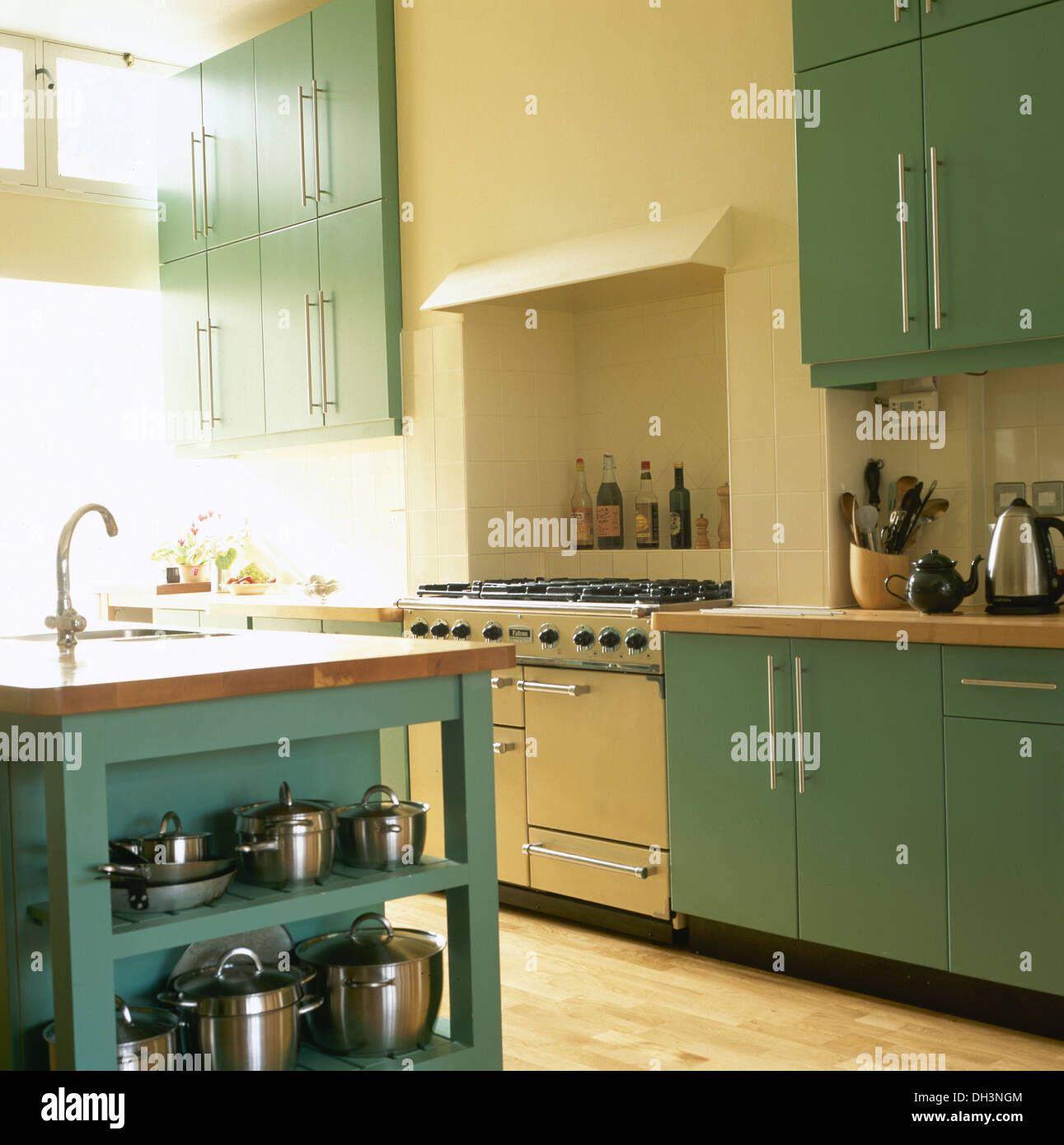 Stainless Steel Saucepans On Green Shelves In Modern Cream Kitchen