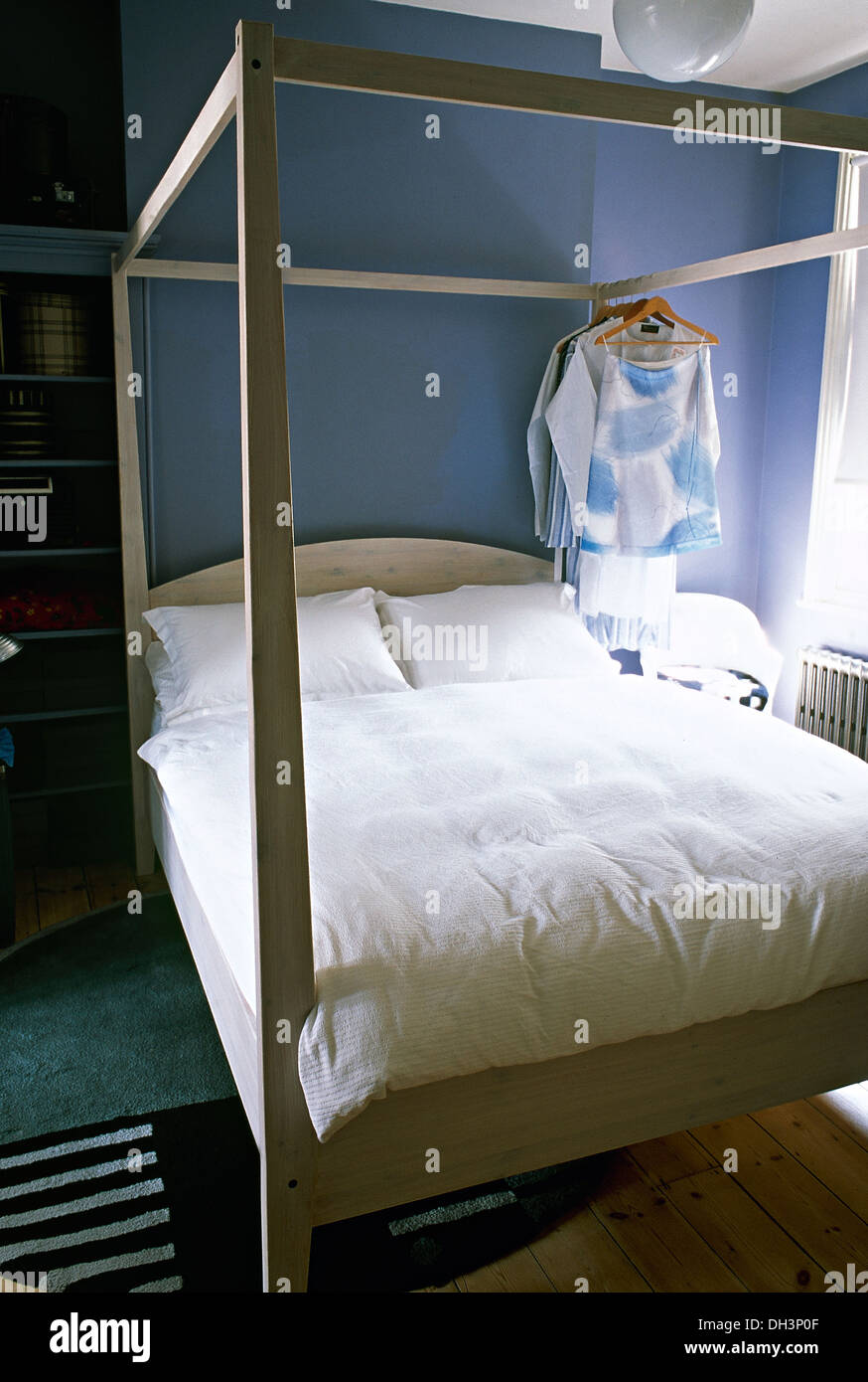 Clothes Hanging From Simple White Four Poster Bed With White
