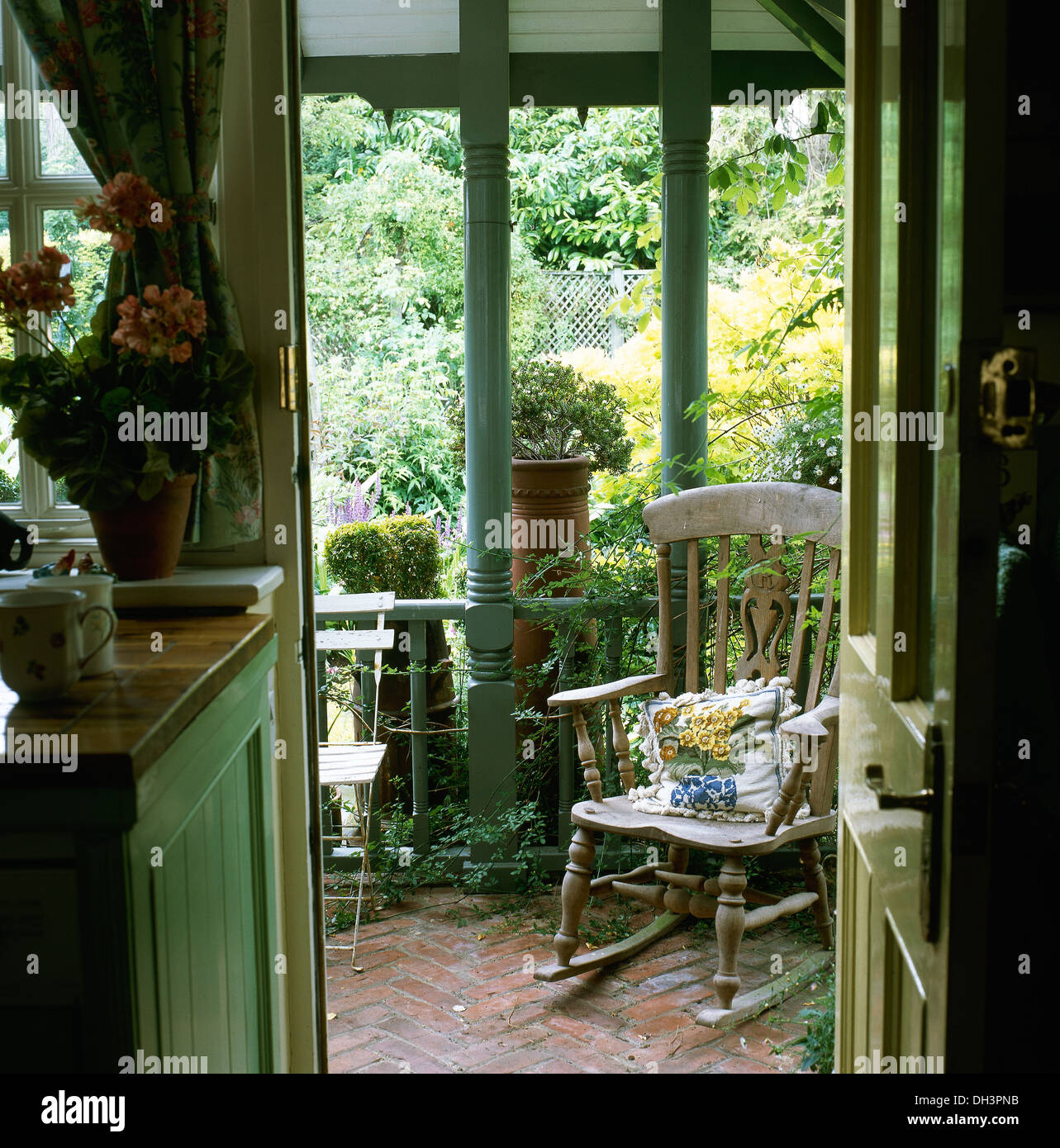 Country kitchen with open door and view of rocking chair on veranda Stock Photo