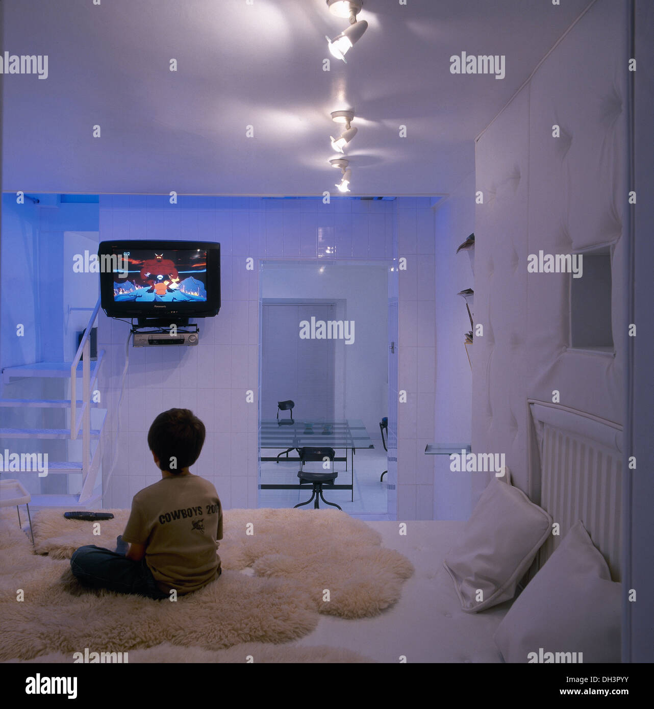 Small Boy Watching Television In Parents Modern Bedroom