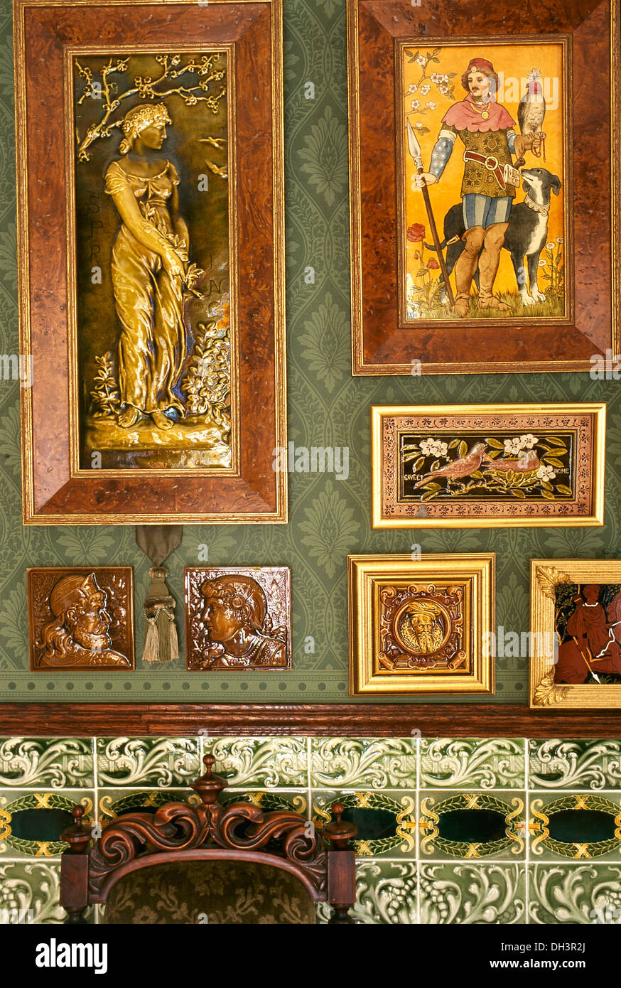 Close-up Arts & Crafts pictures above on green pattern wallpaper above decorative ceramic tiled dado Stock Photo