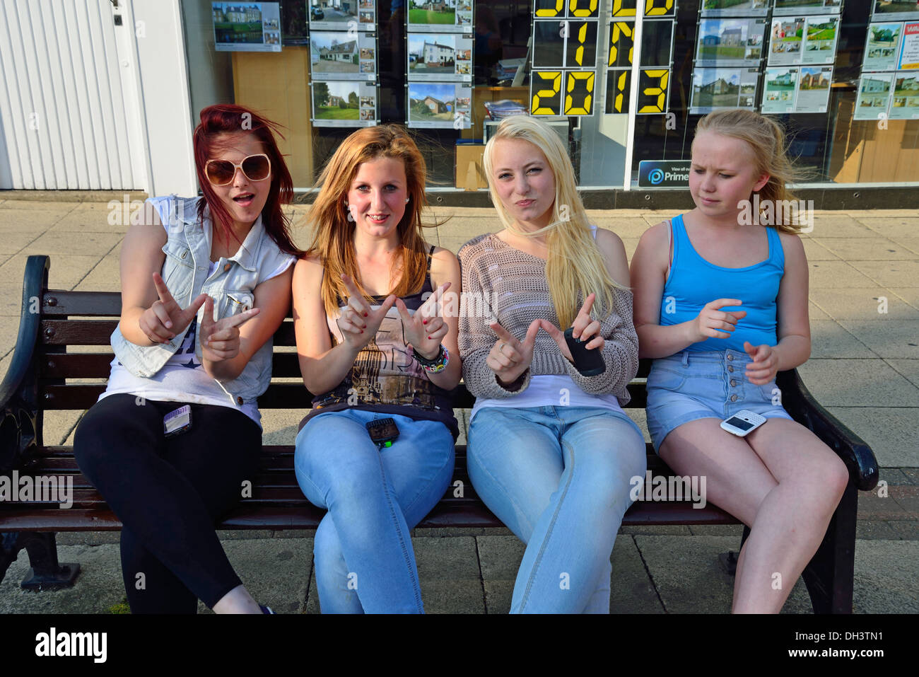 Teenage girls sitting on bench in town centre, Wisbech, Cambridgeshire, England, United Kingdom Stock Photo