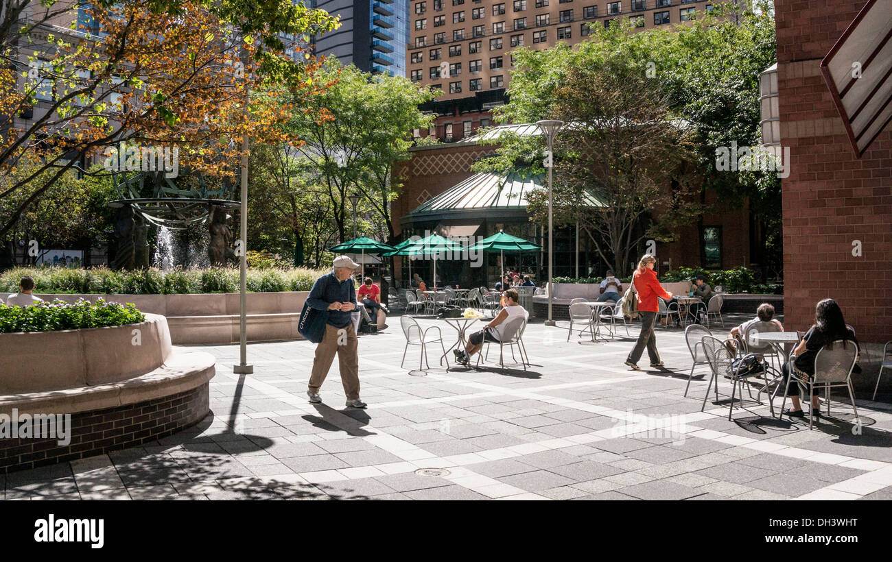 New Yorkers enjoy strolling & sitting in warm autumn sunshine of landscaped outdoor areas Worldwide Plaza Hells Kitchen New York Stock Photo