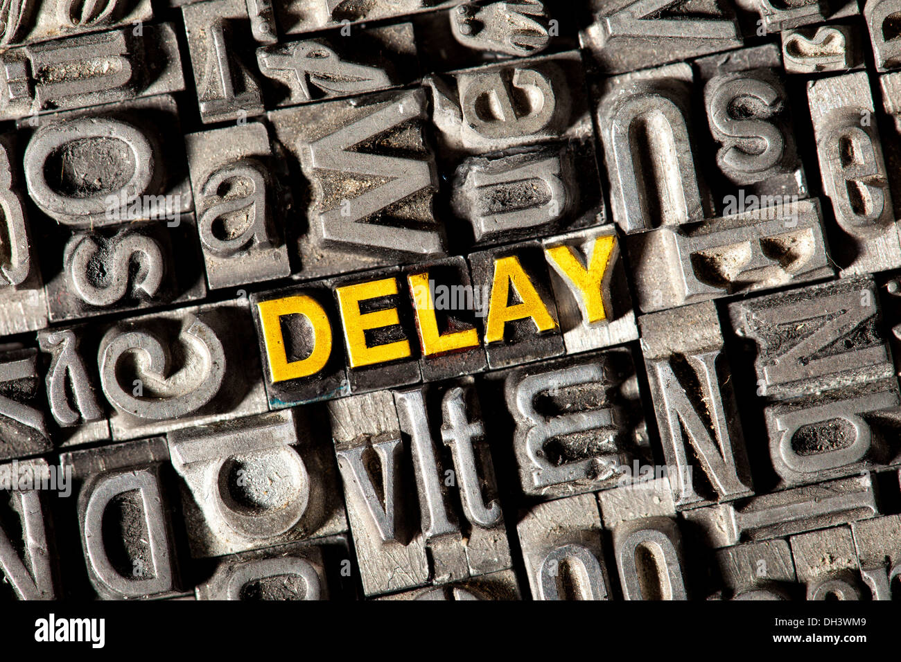 Old lead letters forming the word Delay Stock Photo