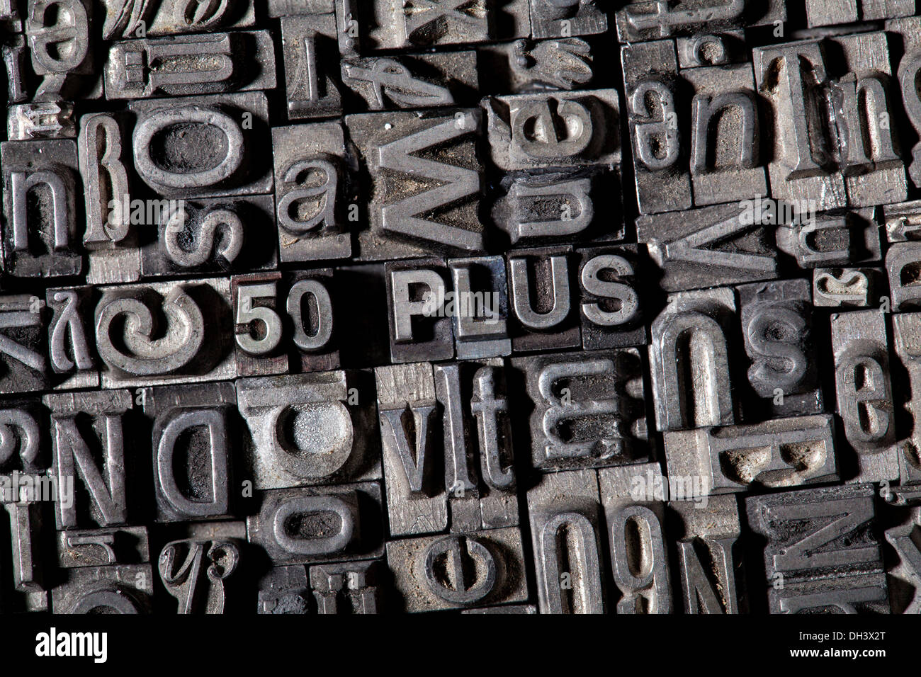 Old lead letters forming the term '50 PLUS' Stock Photo