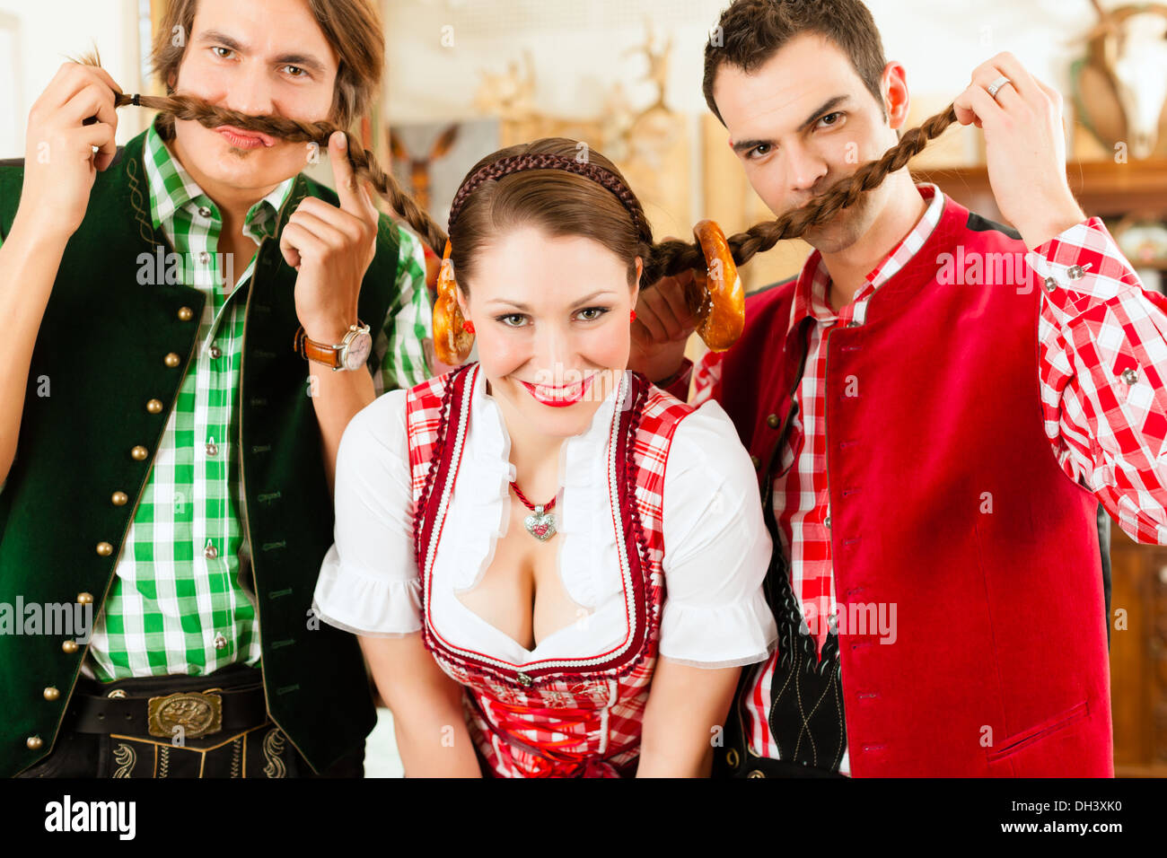 Young people in traditional Bavarian Tracht in restaurant or pub having fun and making jokes Stock Photo
