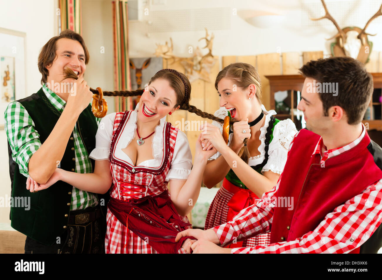 Young people in traditional Bavarian Tracht in restaurant or pub having fun and making jokes Stock Photo