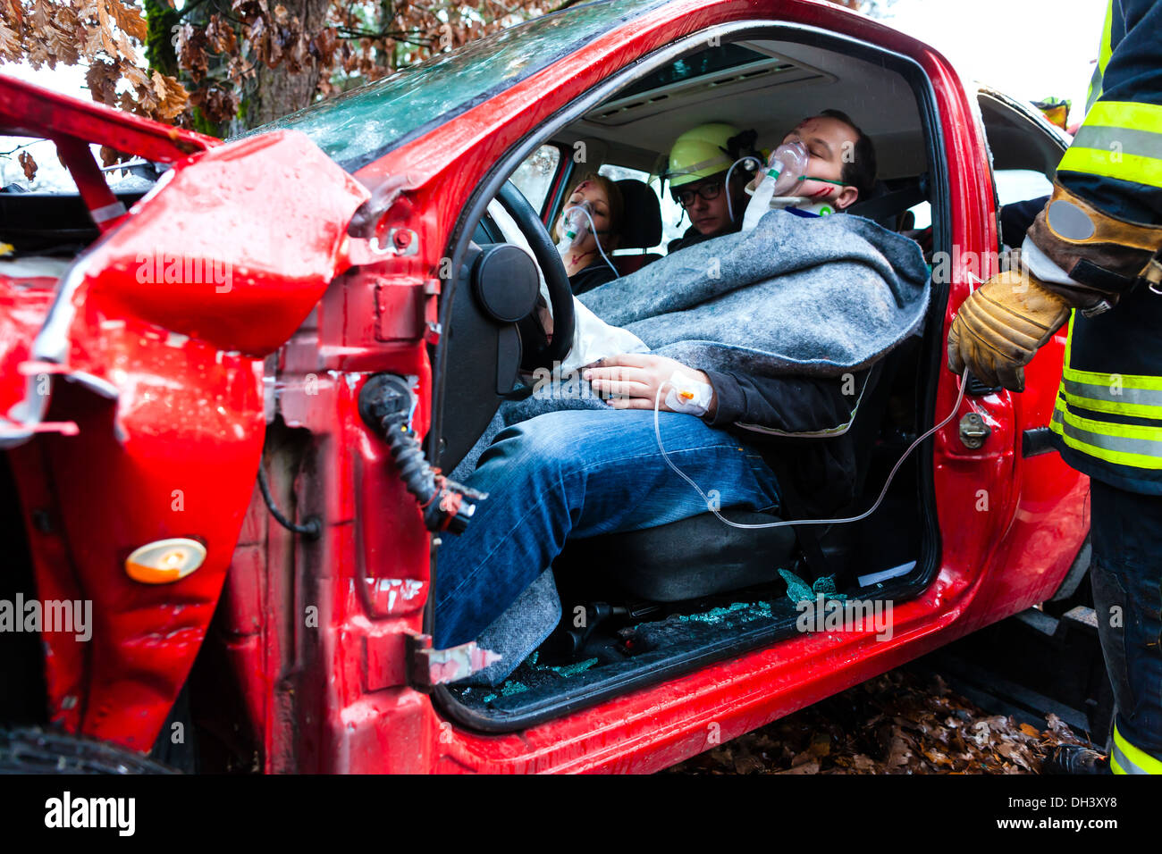 Accident - victim in a crashed vehicle, she receives first aid from firefighters Stock Photo