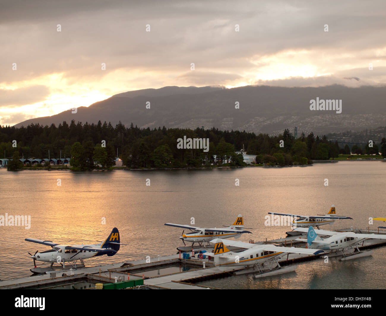 At sunset, five seaplanes are docked at the Vancouver Harbour Flight Centre, Vancouver's downtown seaplane terminal. Stock Photo