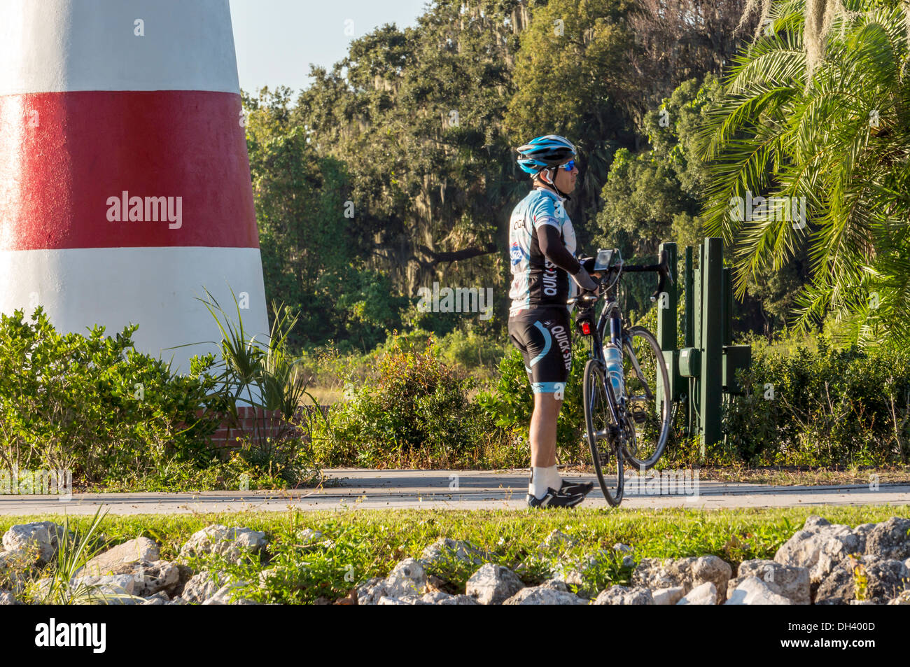 Athletic man with racing bicycle and wearing safety helmet and riding gear at the base of the Mount Dora lighthouse beacon. Stock Photo