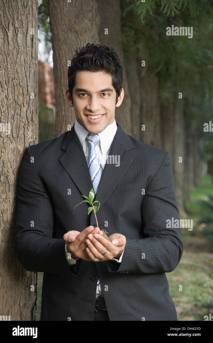 Portrait of a businessman holding a plant and smiling Stock Photo - Alamy